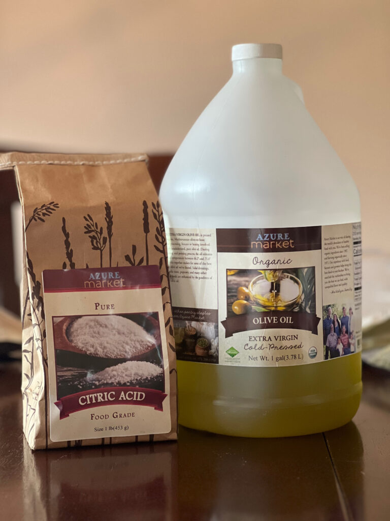 Paper bag of citric acid and gallon jug of olive oil from Azure Standard