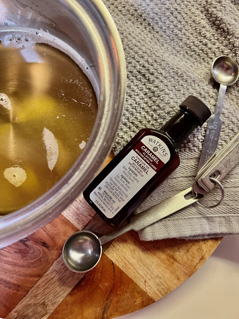 simple syrup in pot next to caramel extract with measuring spoons